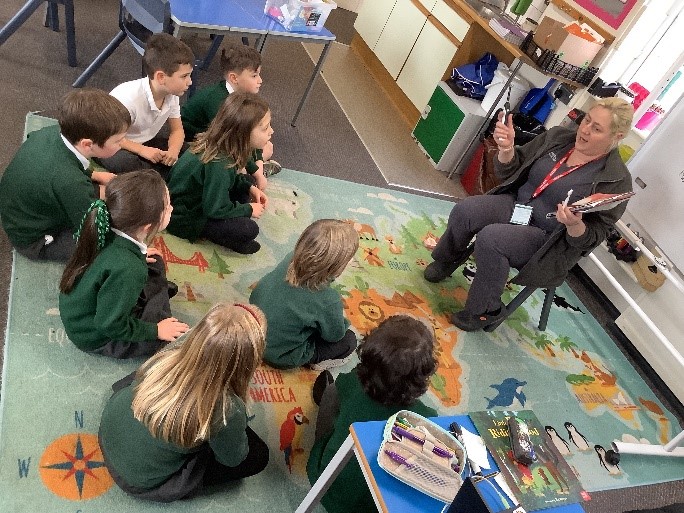 The Dentist holding toothbrushes gives a talk to young children