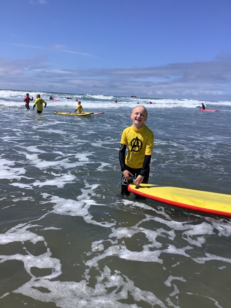 A child standing in the sea with a surf board