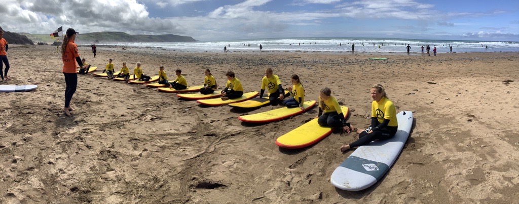 A row of children sat on surf boards on a beach